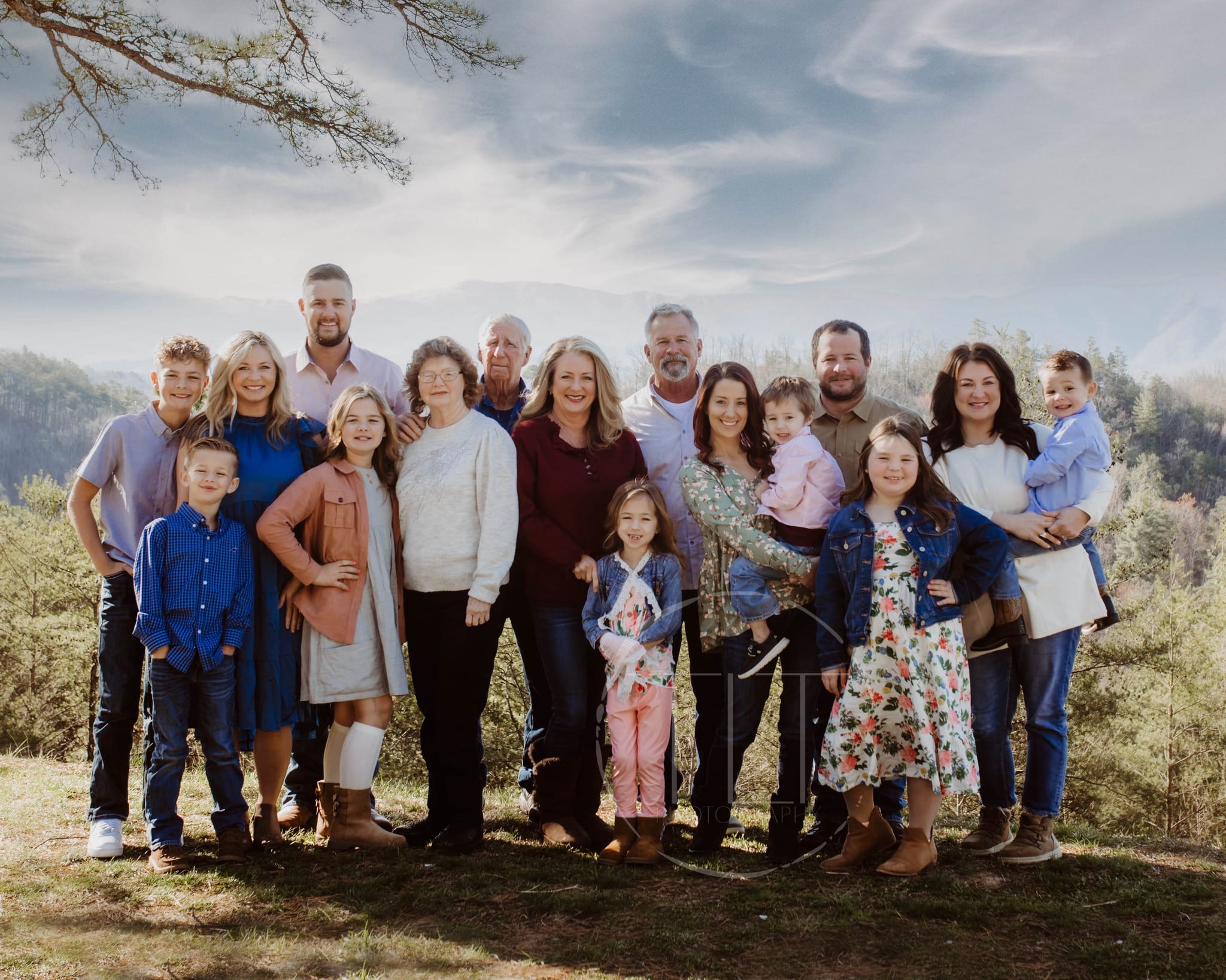 Large family group on grass with a mountain landscape behind them.